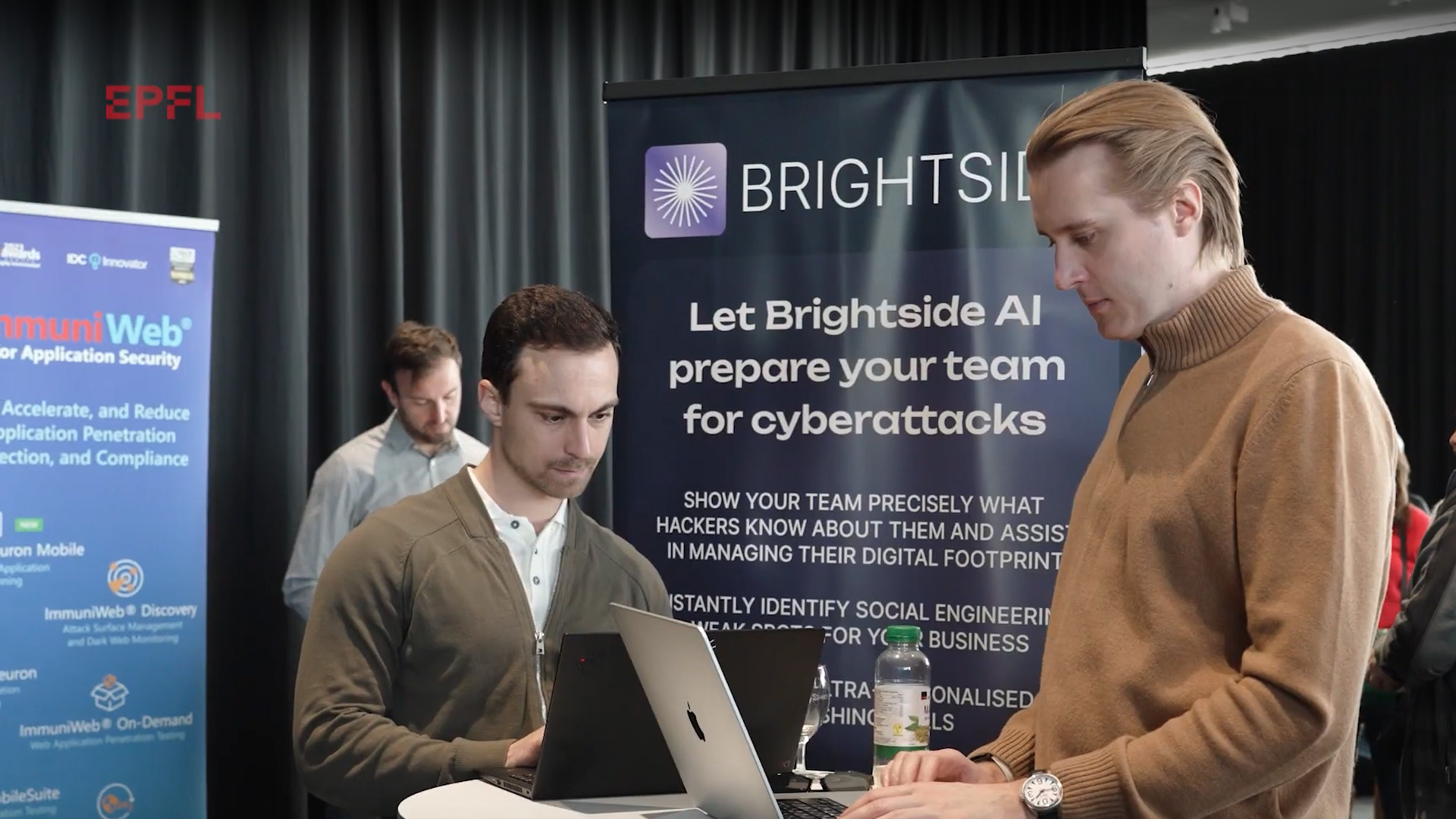 Deux personnes au stand de Brightside, au Forum du Rolex Learning Center, consultant leurs ordinateurs posés sur une table